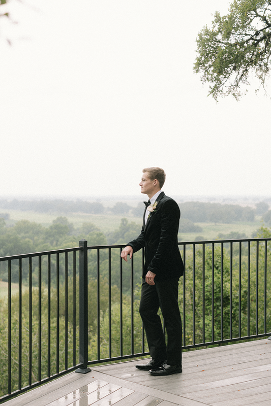 Groom on the balcony at wedding venue in hill country with bow tie and nice suit.
